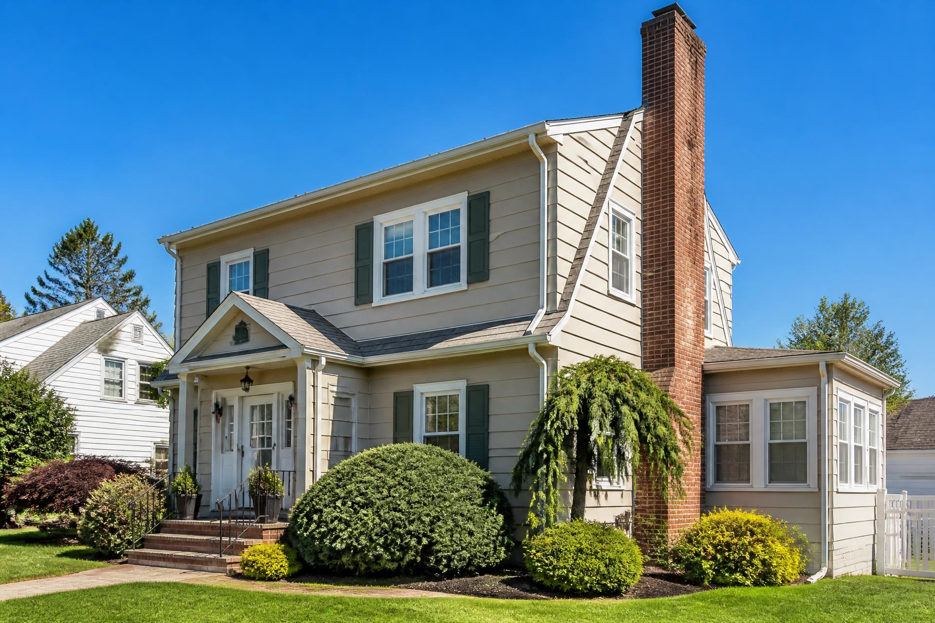 Suburban New Jersey home with a tall brick chimney against a clear blue sky